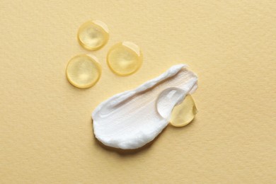 Photo of Samples of transparent gel and white cream on yellow background, flat lay