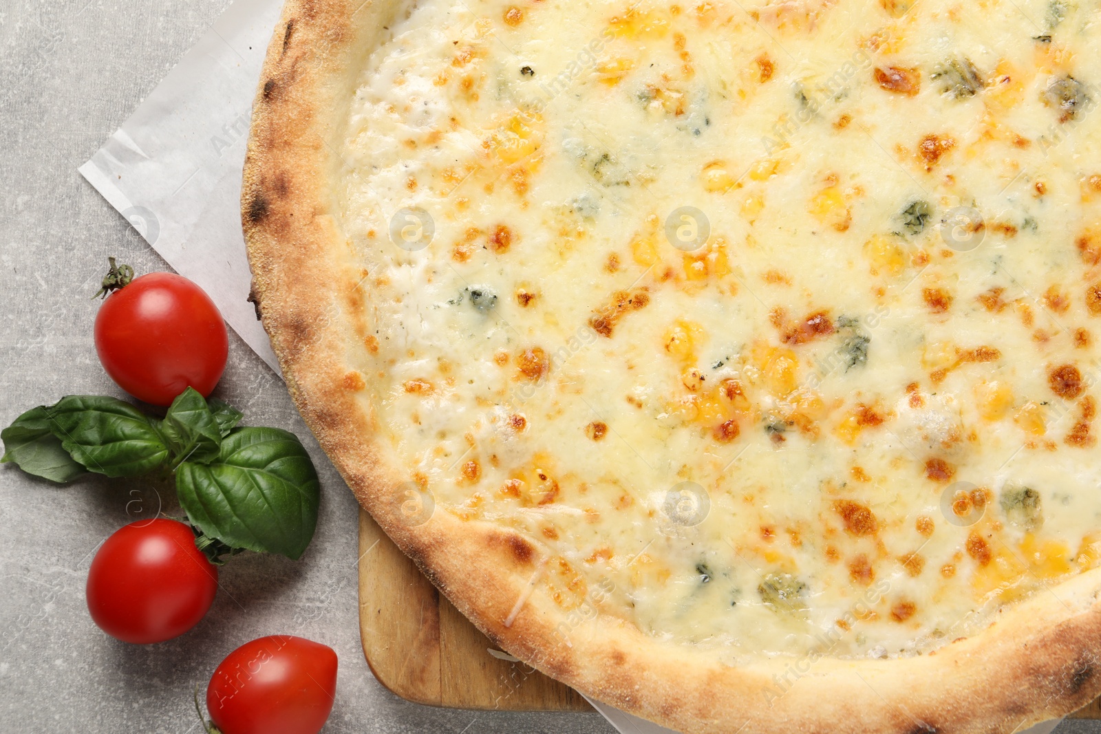 Photo of Delicious cheese pizza, basil and tomatoes on light grey table, flat lay