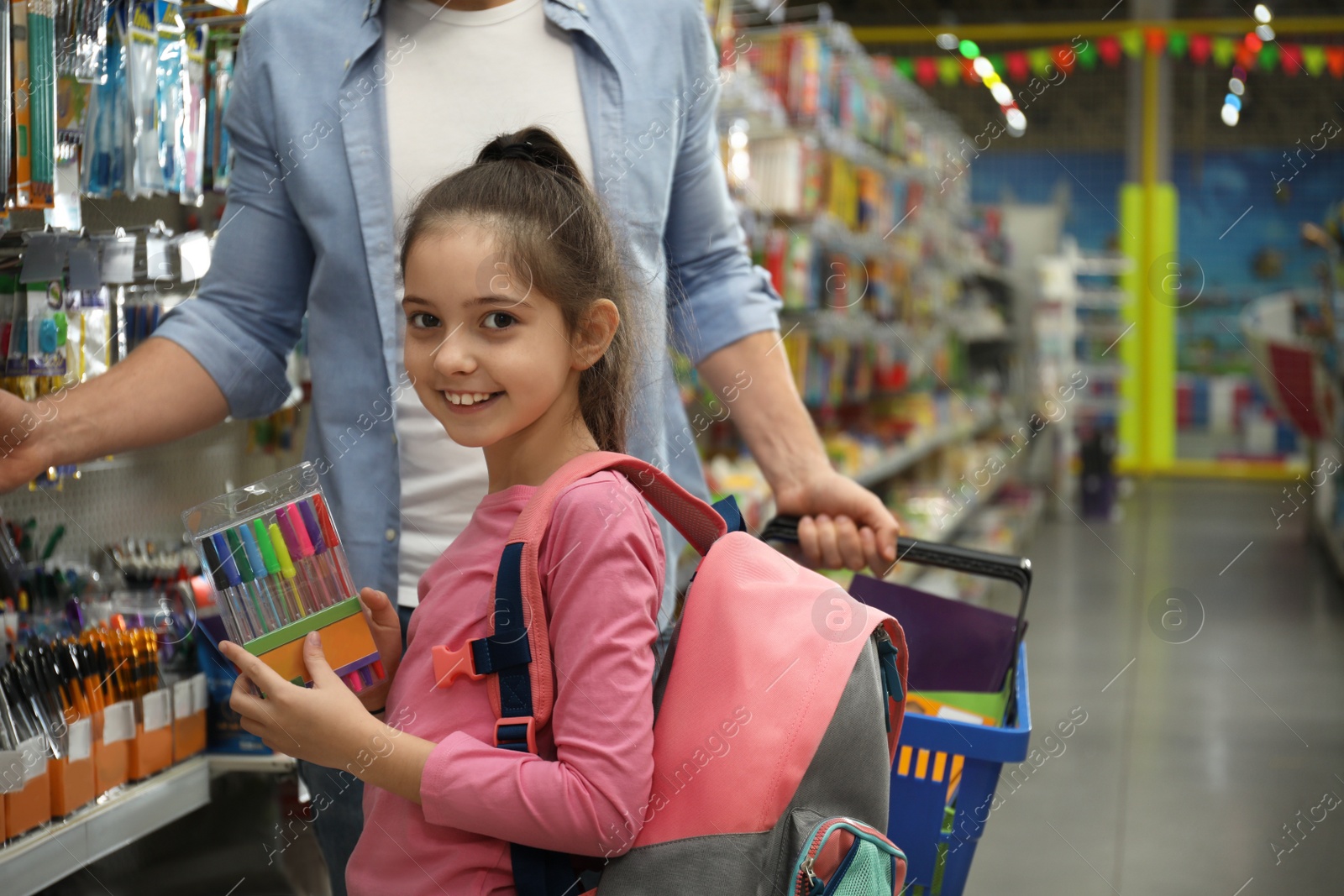 Photo of Little girl with father choosing school stationery in supermarket