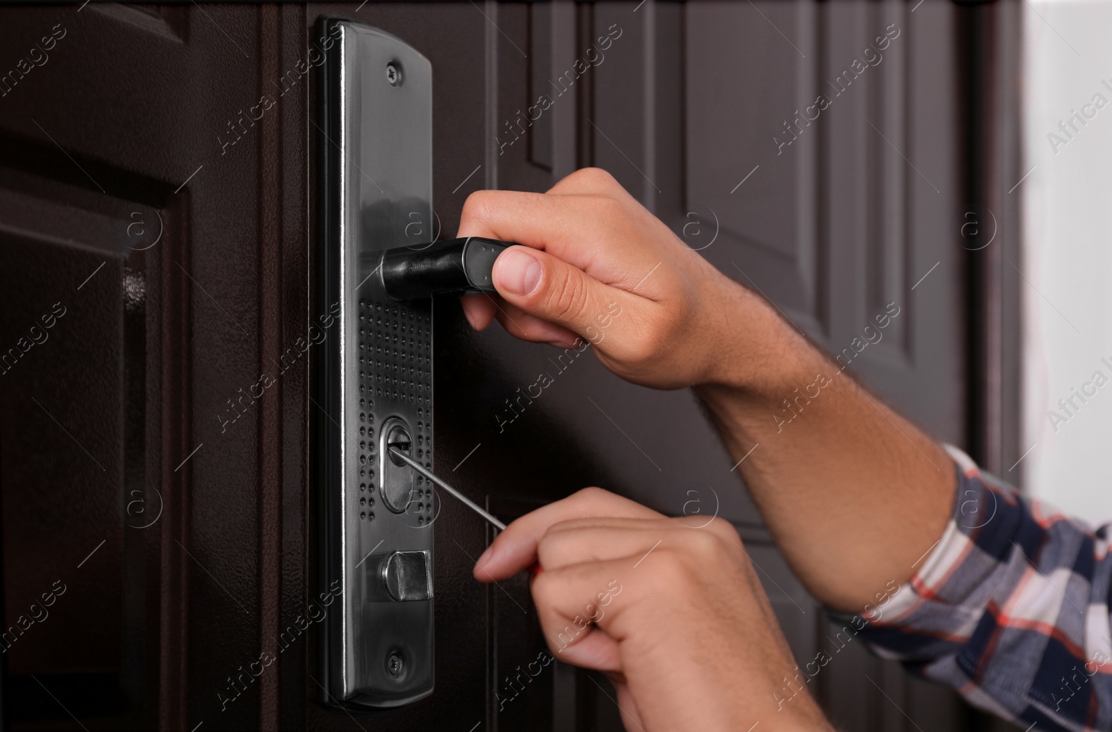 Photo of Handyman with screwdriver repairing door lock, closeup