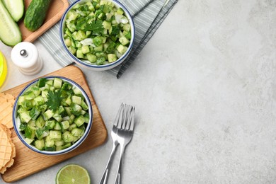 Photo of Bowls of delicious cucumber salad served on light table, flat lay. Space for text