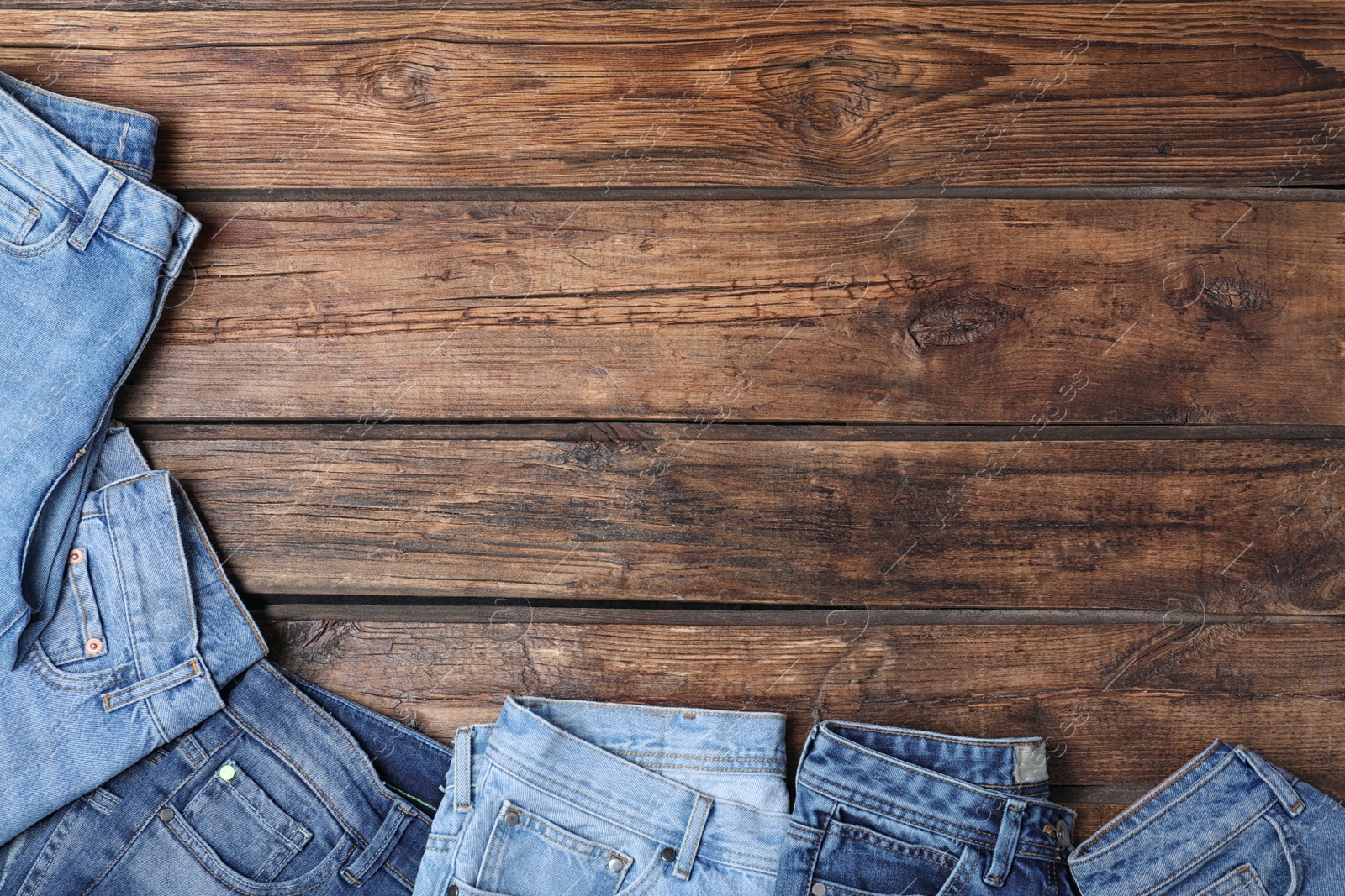 Photo of Collection of stylish jeans on wooden background, flat lay. Space for text
