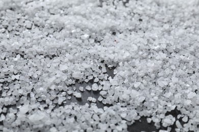 Photo of Scattered natural salt on black table, closeup