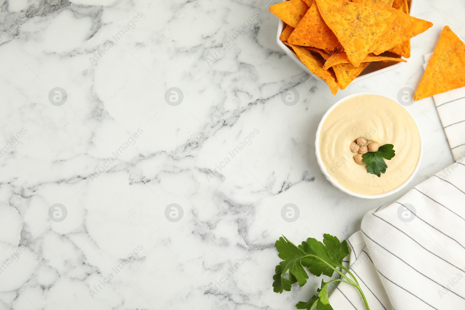 Photo of Delicious hummus with nachos on white marble table, flat lay. Space for text