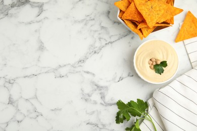 Delicious hummus with nachos on white marble table, flat lay. Space for text