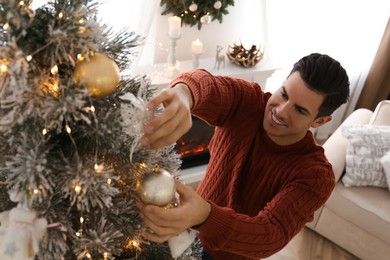 Photo of Man decorating Christmas tree at home, above view. Interior design