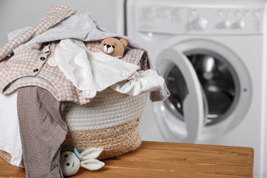 Photo of Laundry basket with baby clothes and toys on table in bathroom, closeup. Space for text