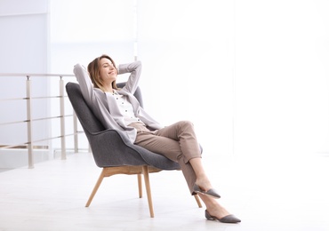 Photo of Beautiful young businesswoman relaxing in armchair indoors. Space for text