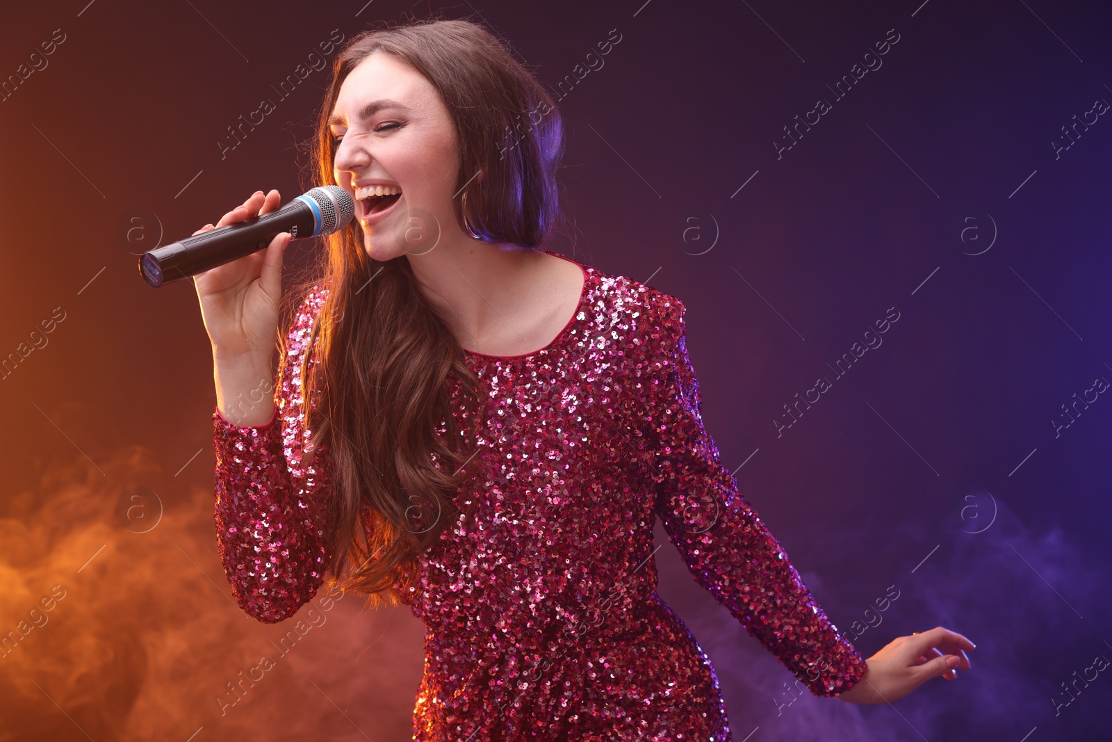 Photo of Emotional woman with microphone singing in color lights