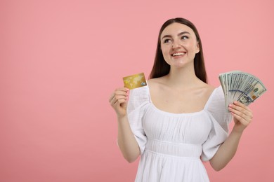 Photo of Happy woman with credit card and dollar banknotes on pink background