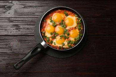 Photo of Delicious shakshuka in frying pan on wooden table, top view