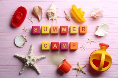 Flat lay composition with phrase SUMMER CAMP made of cubes on pink wooden background