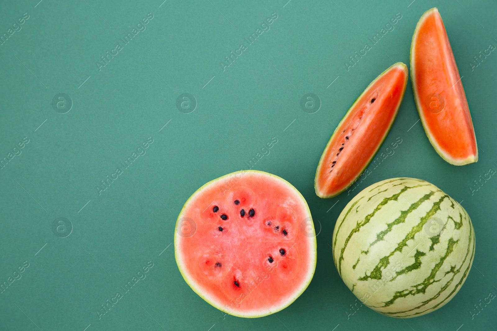 Photo of Cut and whole ripe watermelons on teal background, flat lay. Space for text