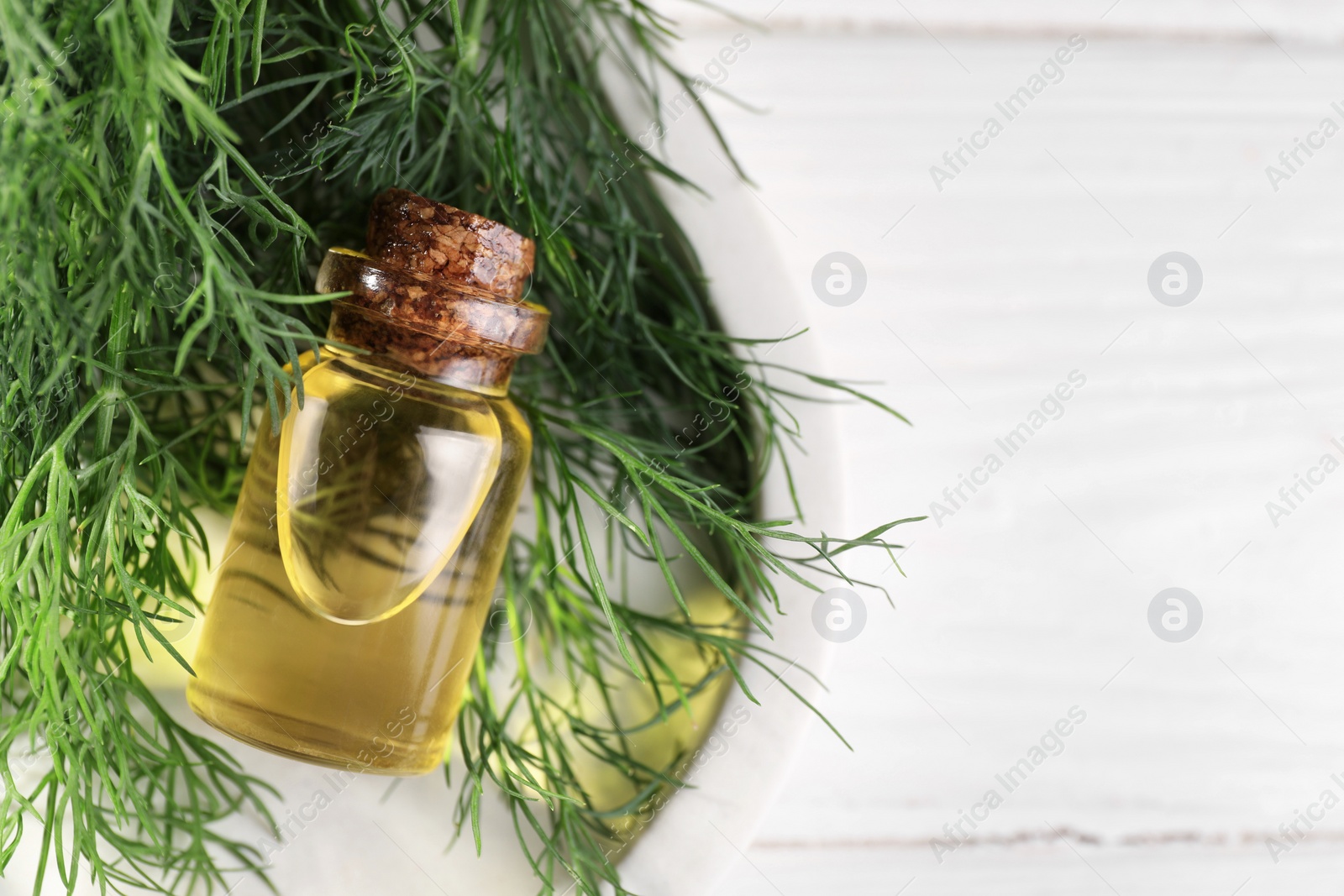 Photo of Bottle of essential oil and fresh dill on white table, top view. Space for text