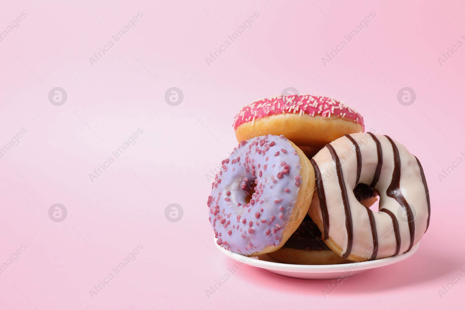 Photo of Tasty glazed donuts on pink background, space for text