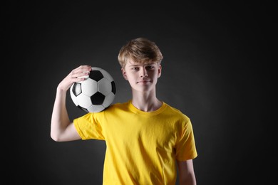 Teenage boy with soccer ball on black background