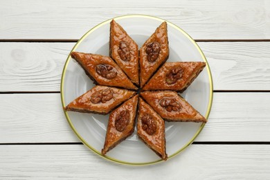 Photo of Delicious sweet baklava with walnuts on white wooden table, top view