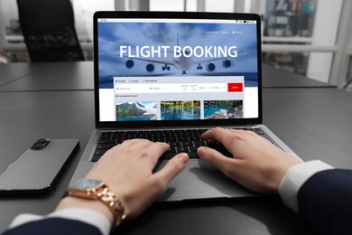 Image of Woman using laptop to book flight at black table, closeup
