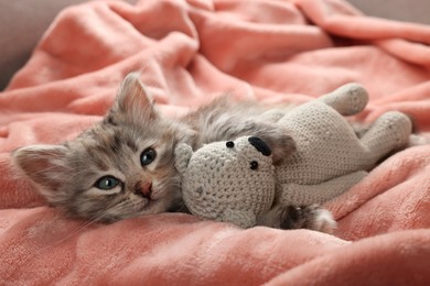 Photo of Cute kitten with toy on soft pink blanket