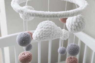 Photo of Modern baby mobile under crib near beige wall in room, closeup