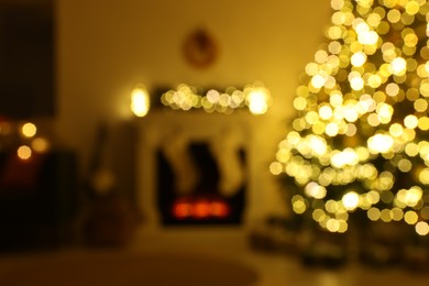 Stylish fireplace near decorated Christmas tree in cosy room, blurred view