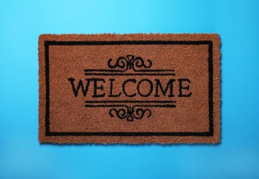 Photo of Doormat with word Welcome on light blue background, top view