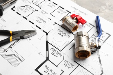 Photo of House plan with plumber's items on grey table, closeup