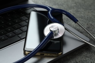 Modern electronic devices and stethoscope on grey table, closeup