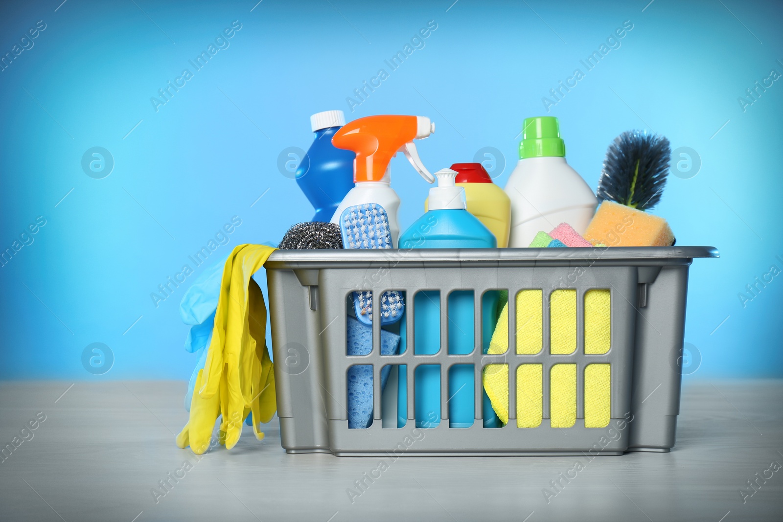 Photo of Basket with different cleaning products and supplies on light table