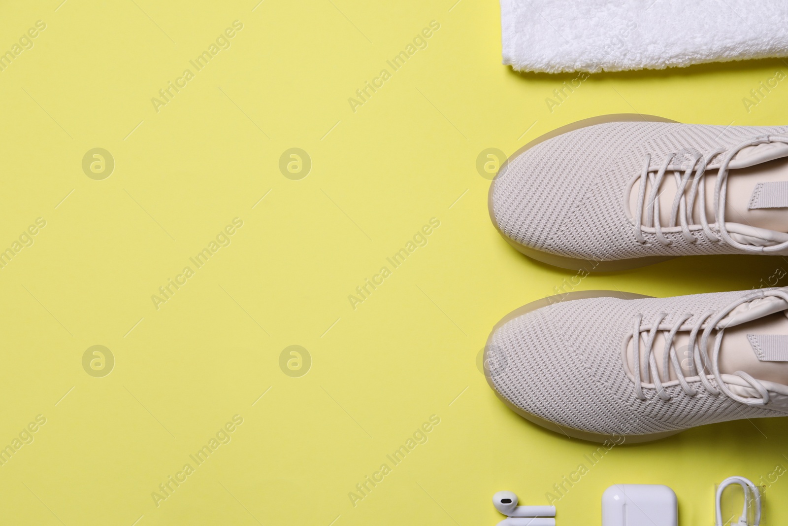 Photo of Sneakers, towel and earphones on color background, flat lay. Space for text