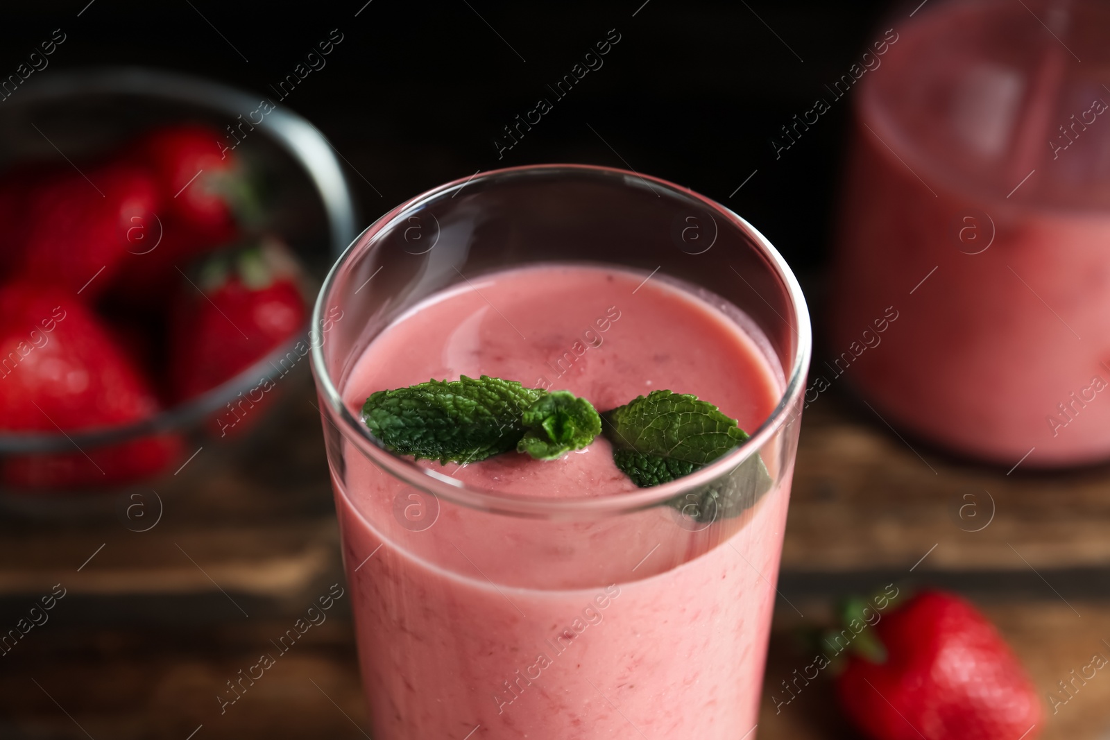 Photo of Tasty strawberry smoothie with mint in glass on table, closeup