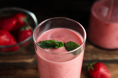 Photo of Tasty strawberry smoothie with mint in glass on table, closeup