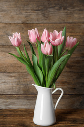 Photo of Beautiful pink spring tulips in vase on wooden table