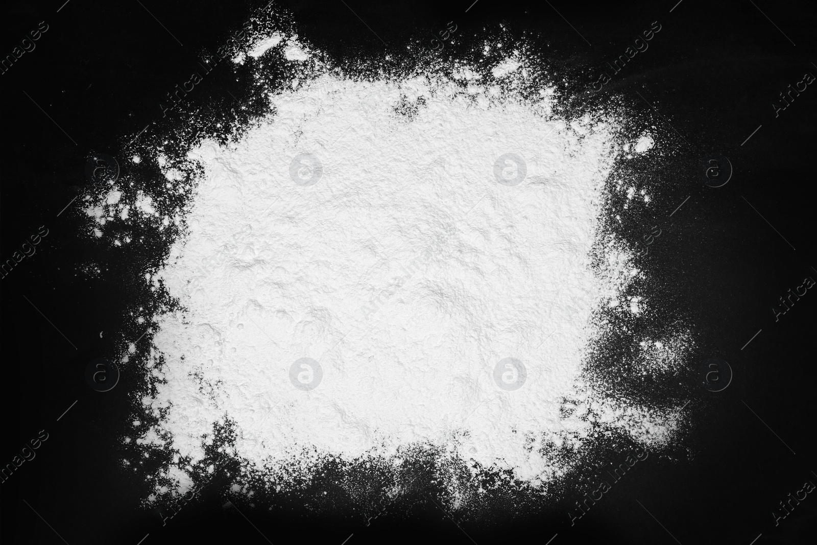 Photo of Pile of flour on black table, top view