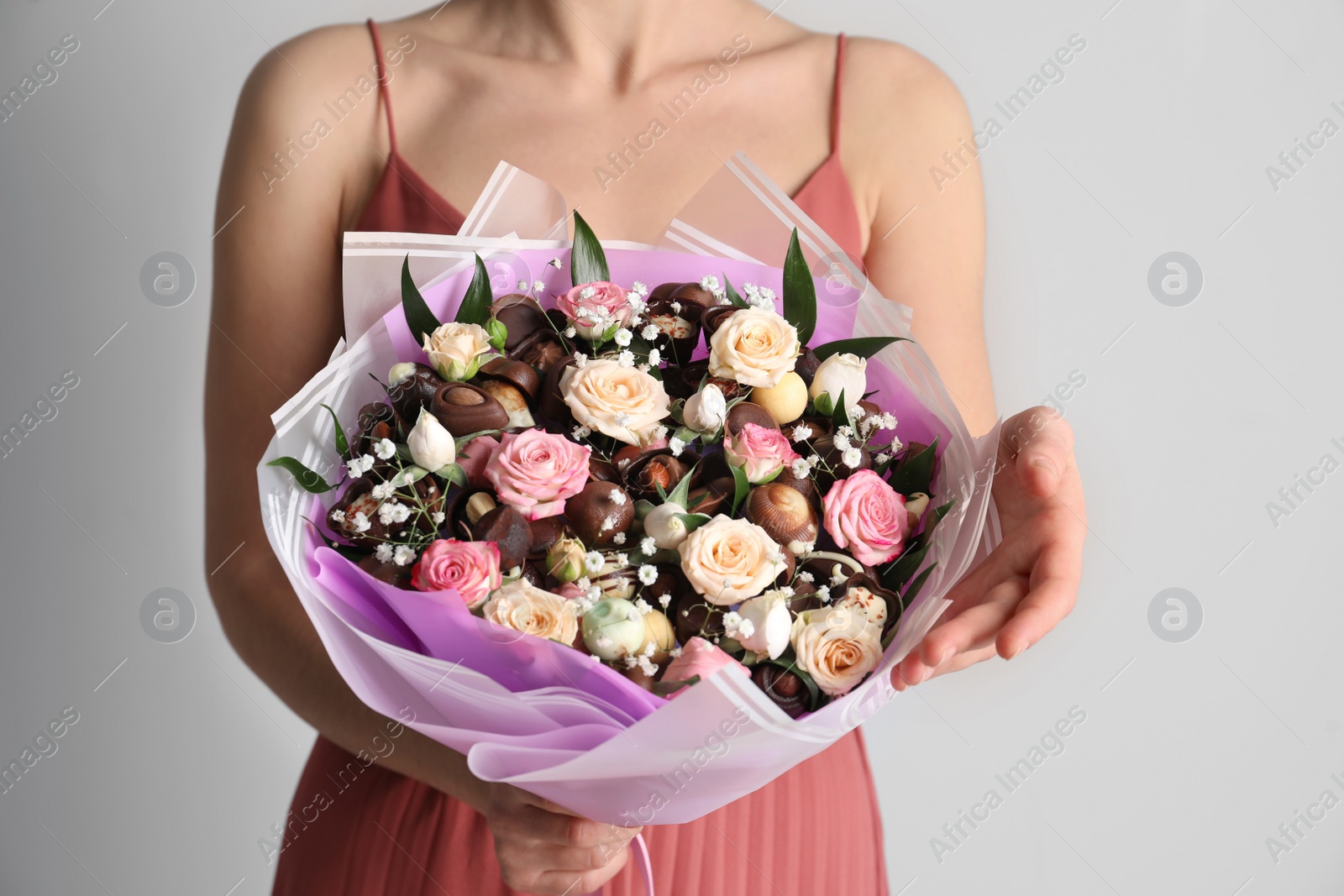 Photo of Woman with beautiful food bouquet on light grey background, closeup