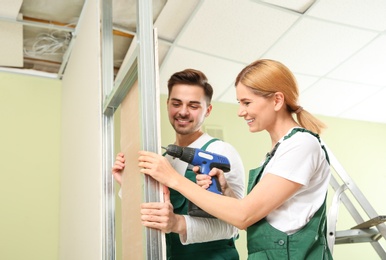 Photo of Workers installing drywall indoors. Home repair service