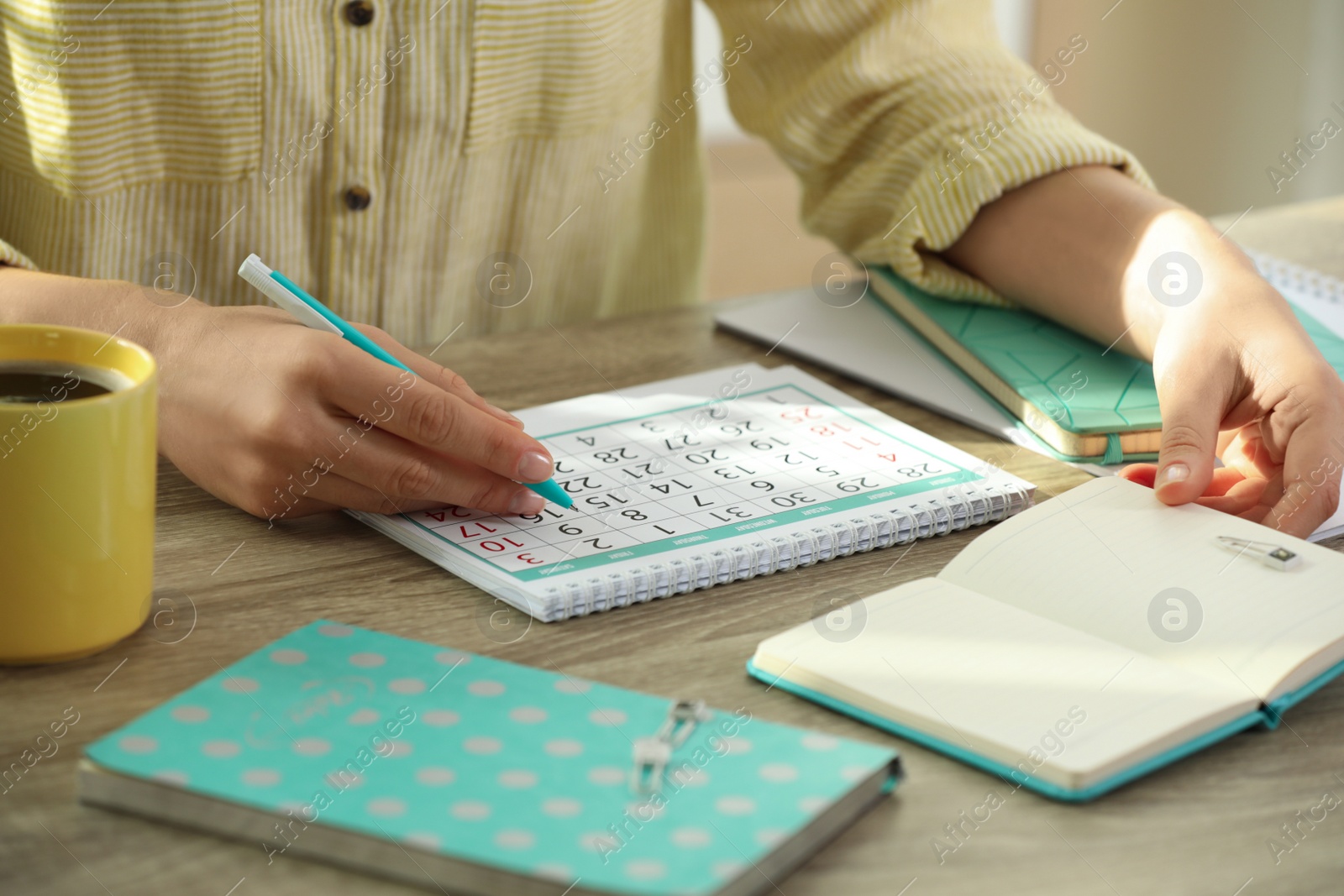 Photo of Woman making schedule using calendar at wooden table, closeup