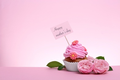 Photo of Tasty cupcake and flowers for Mother's Day on color background