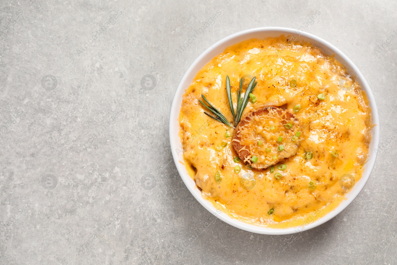 Photo of Tasty homemade French onion soup on grey table, top view. Space for text