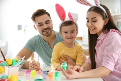 Photo of Happy family painting Easter eggs in kitchen. Festive tradition