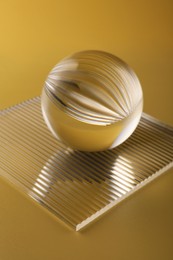 View of transparent glass ball on yellow background