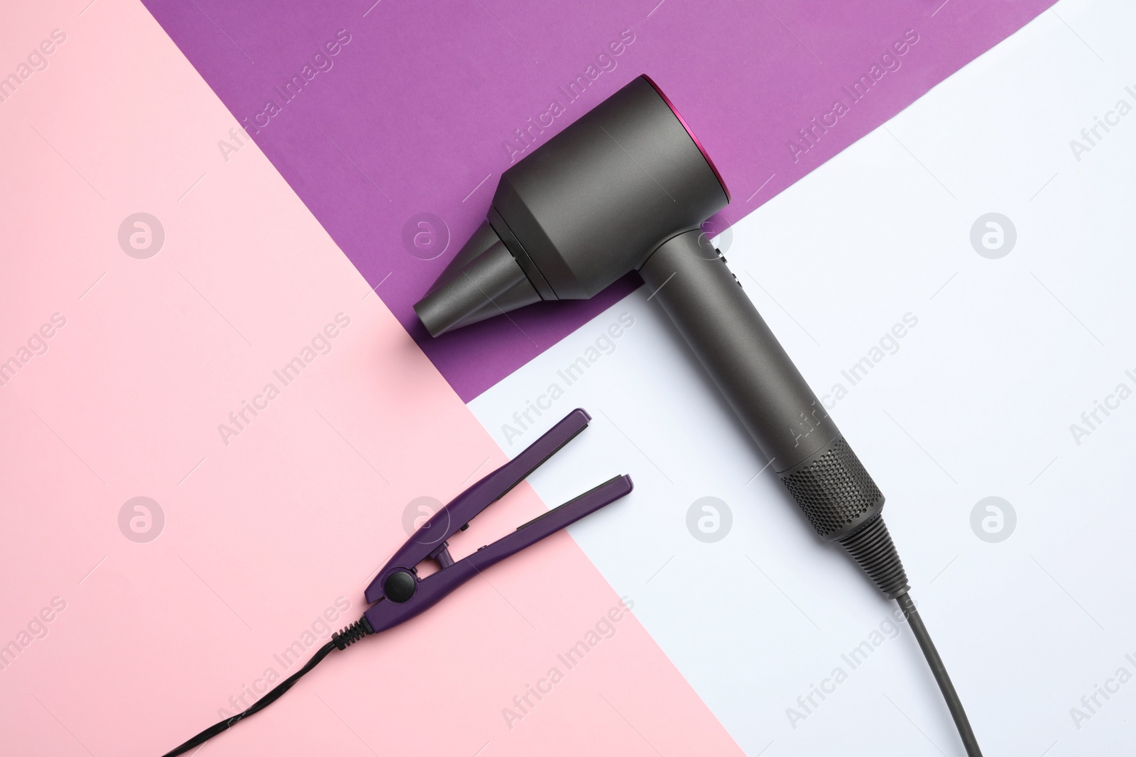 Photo of Hair dryer and iron on color background, flat lay. Professional hairdresser tool