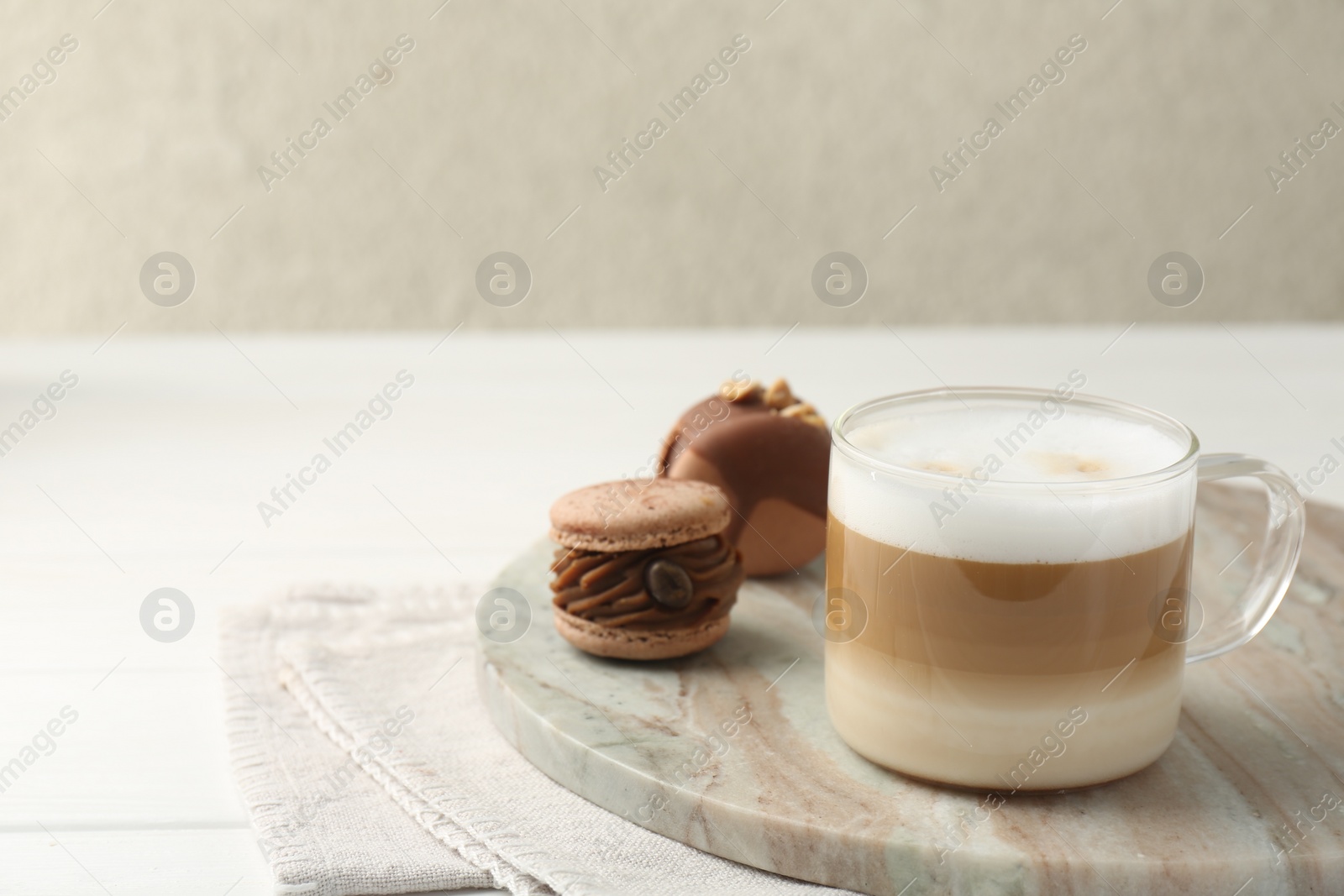 Photo of Aromatic coffee in cup and tasty macarons on white wooden table, space for text