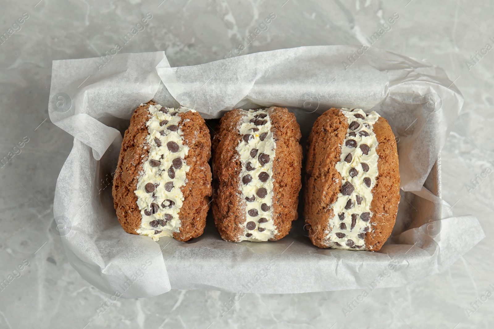 Photo of Sweet delicious ice cream cookie sandwiches with chocolate chips served on table, top view