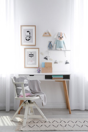 Photo of Stylish child's room interior with desk and beautiful pictures