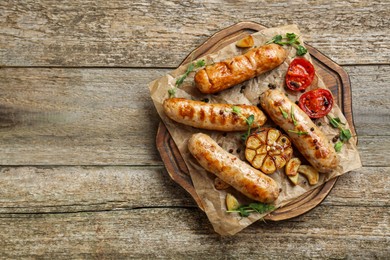 Photo of Tasty fresh grilled sausages with vegetables on wooden table, top view. Space for text