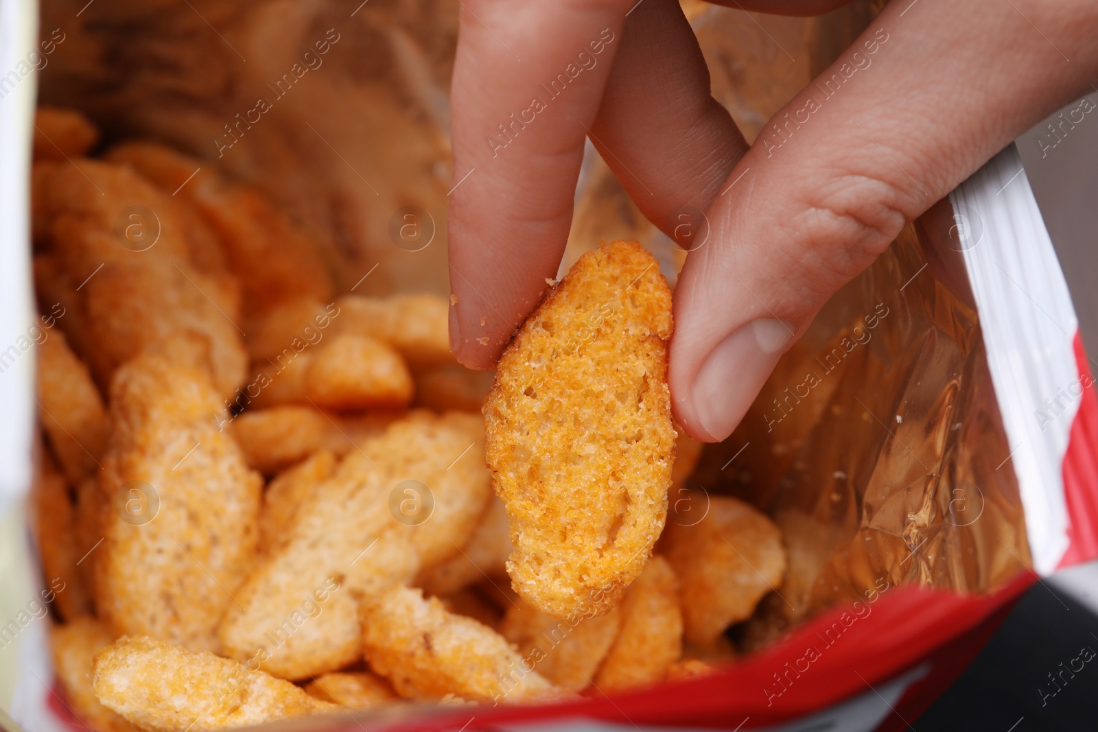 Photo of Woman taking crispy rusk out of package, closeup