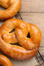 Photo of Cooling rack with delicious freshly baked pretzels on wooden table, top view