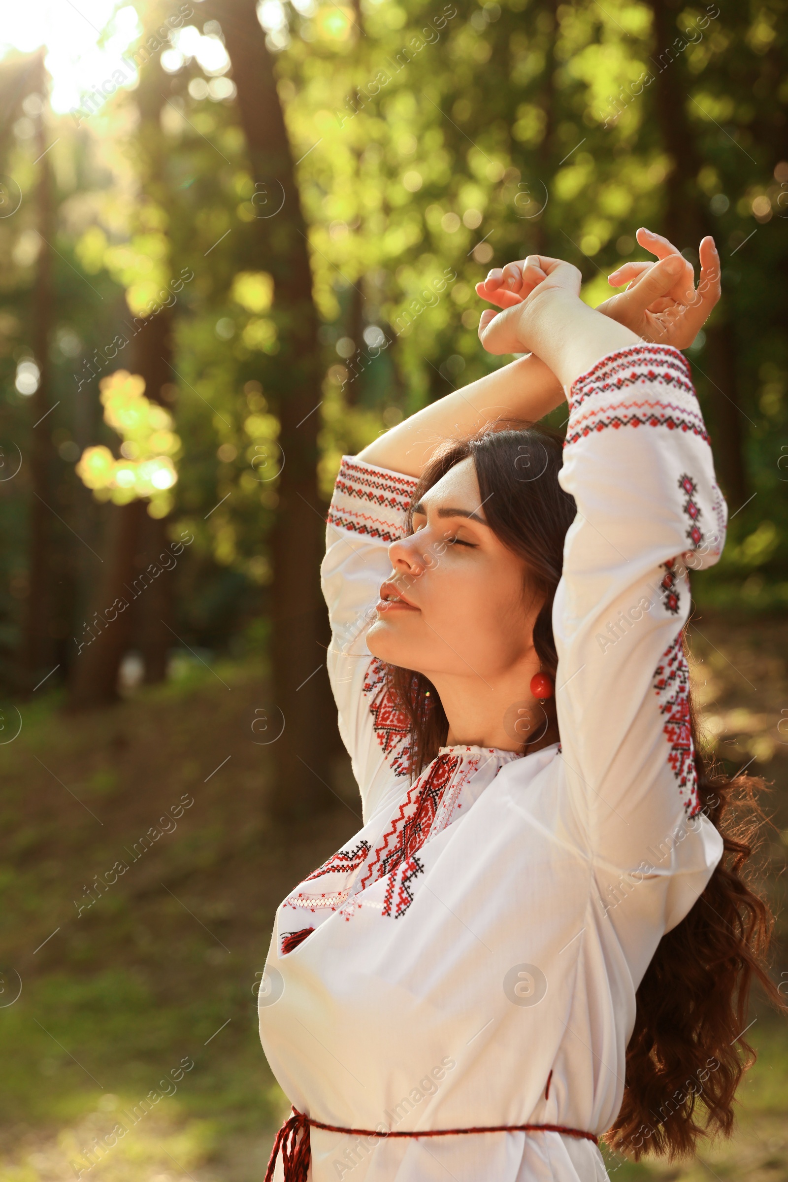 Photo of Beautiful woman in embroidered shirt outdoors. Ukrainian national clothes