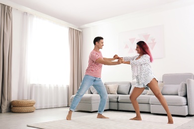 Beautiful happy couple dancing in living room at home